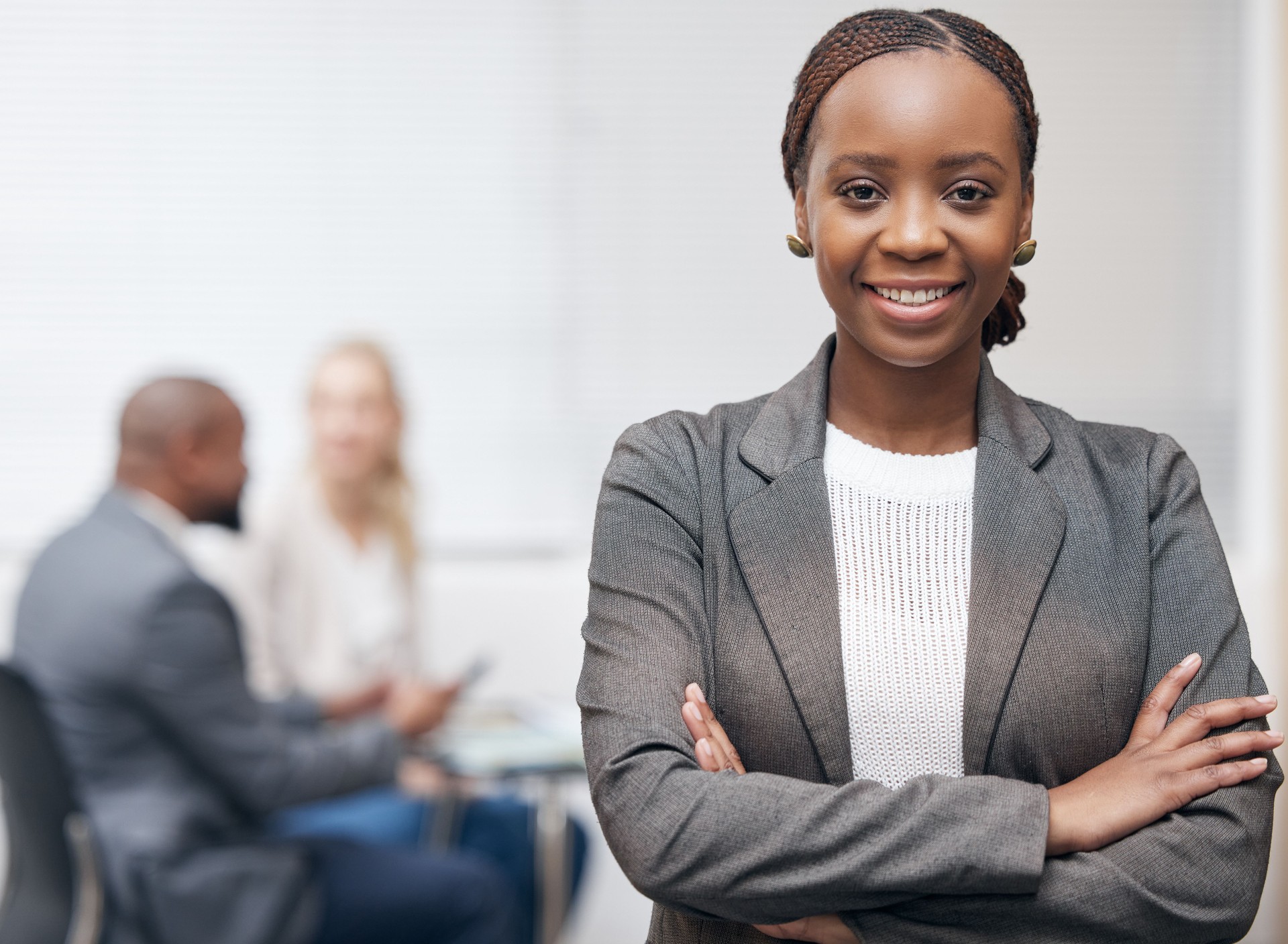 Portrait of a confident young businesswoman standing with her arms crossed in an office with her colleagues in the background